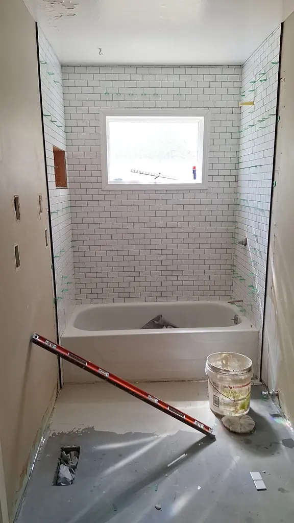 Bathroom mid-remodel with the subway tile set and the floor still bare, Knoxville, Tennessee